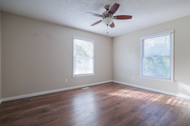 spare room with visible vents, baseboards, dark wood finished floors, and a textured ceiling