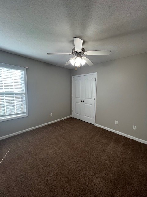 3664 Druid Oaks Dr, Valdosta, GA 31602 - unfurnished bedroom with a closet, baseboards, dark carpet, and a textured ceiling