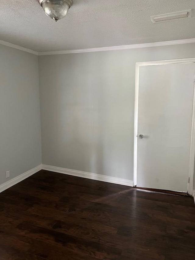 spare room featuring dark hardwood / wood-style flooring, a textured ceiling, and ornamental molding