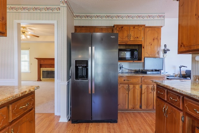 kitchen with stainless steel fridge, light wood-style flooring, black microwave, and wallpapered walls