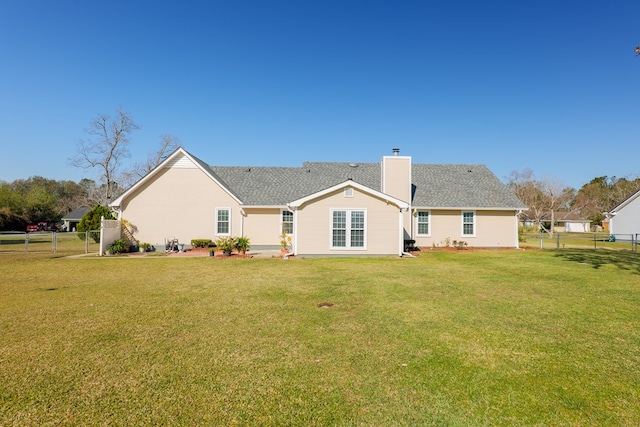 rear view of house featuring a lawn, roof with shingles, a chimney, and fence