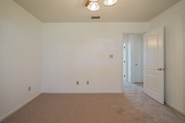 unfurnished room featuring visible vents, light carpet, and baseboards