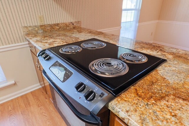 interior details with light wood finished floors, stainless steel electric range, and wallpapered walls