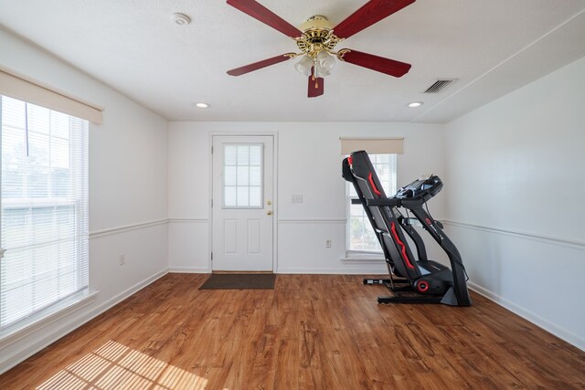 exercise area featuring visible vents, a healthy amount of sunlight, baseboards, and wood finished floors