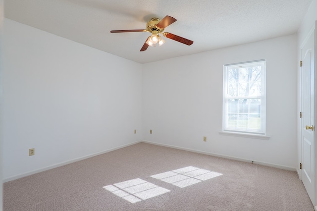 spare room featuring a textured ceiling, a ceiling fan, baseboards, and light carpet