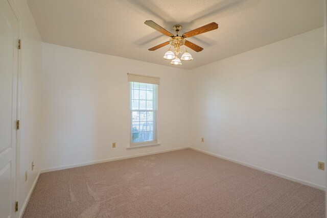 empty room featuring light colored carpet, baseboards, and ceiling fan