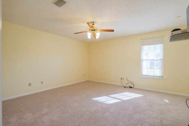 empty room featuring baseboards, carpet flooring, a textured ceiling, and visible vents