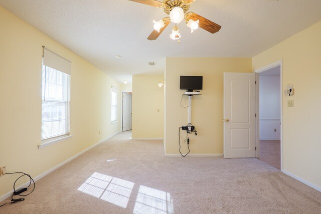 unfurnished room featuring ceiling fan, light colored carpet, baseboards, and a textured ceiling