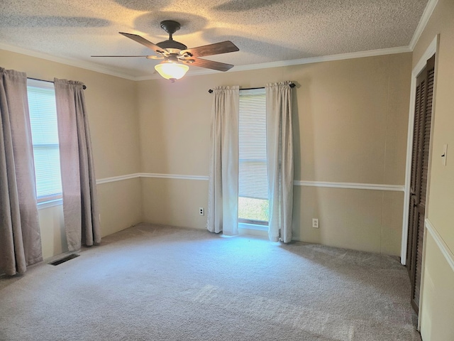 carpeted empty room featuring visible vents, a wealth of natural light, a textured ceiling, and ceiling fan