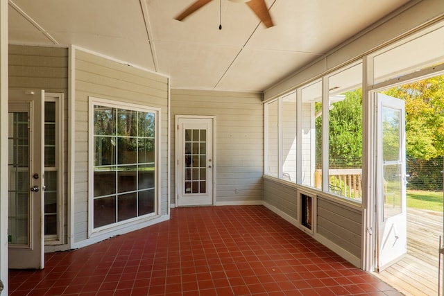 unfurnished sunroom featuring ceiling fan and a healthy amount of sunlight