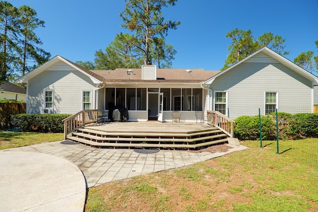 rear view of house with a yard, a deck, and a sunroom