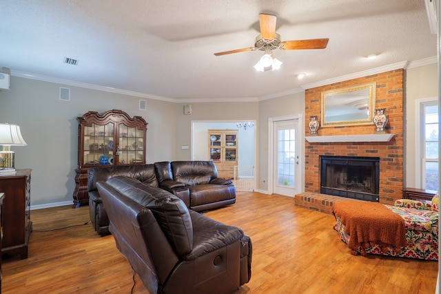 living room with plenty of natural light, light hardwood / wood-style floors, a textured ceiling, and ornamental molding