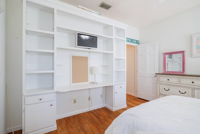 bedroom with hardwood / wood-style floors and a textured ceiling