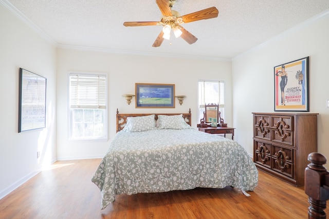 bedroom featuring hardwood / wood-style floors, ceiling fan, ornamental molding, and a textured ceiling