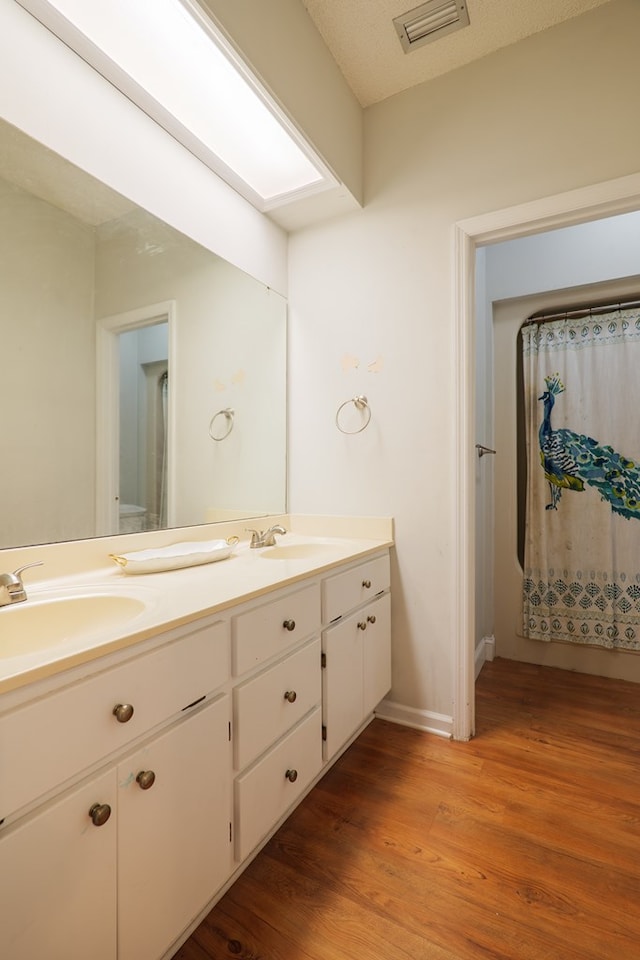 bathroom with hardwood / wood-style floors, vanity, and a textured ceiling