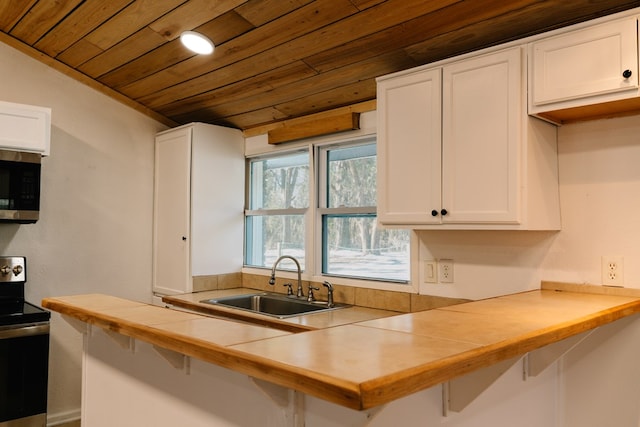 kitchen with a kitchen bar, appliances with stainless steel finishes, white cabinets, and a sink