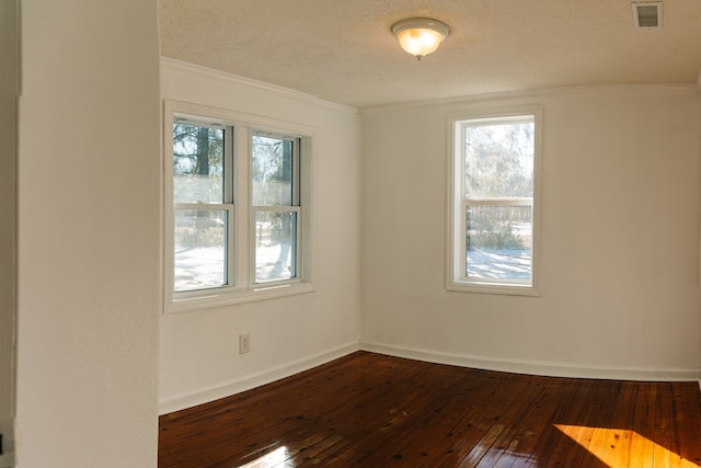 unfurnished room featuring visible vents, ornamental molding, a textured ceiling, wood finished floors, and baseboards