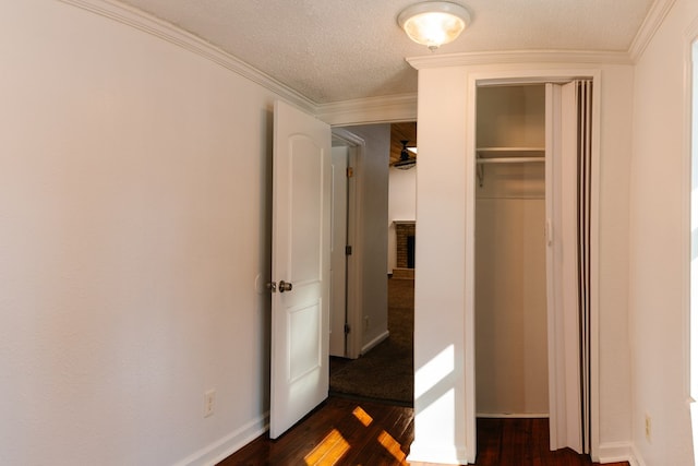 unfurnished bedroom featuring a textured ceiling, baseboards, dark wood-style flooring, and crown molding