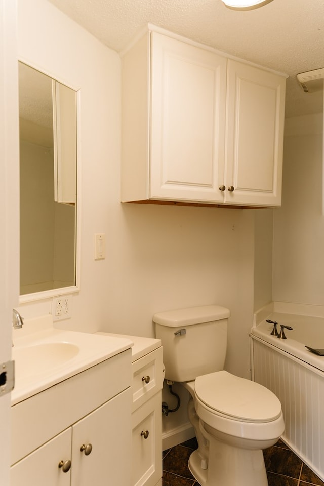 bathroom with a bath, vanity, toilet, and a textured ceiling