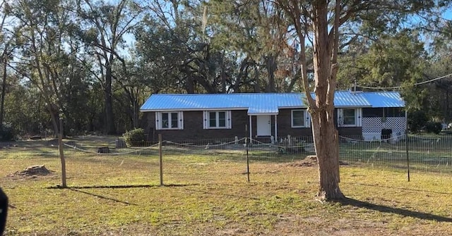 ranch-style home with metal roof, a fenced front yard, and a front yard