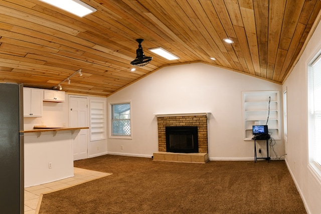 unfurnished living room with lofted ceiling, a brick fireplace, wood ceiling, and light colored carpet