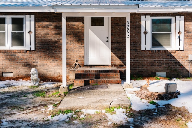 entrance to property featuring metal roof, brick siding, and crawl space