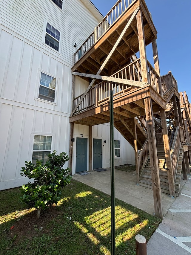 exterior space with stairs, a patio area, board and batten siding, and a deck