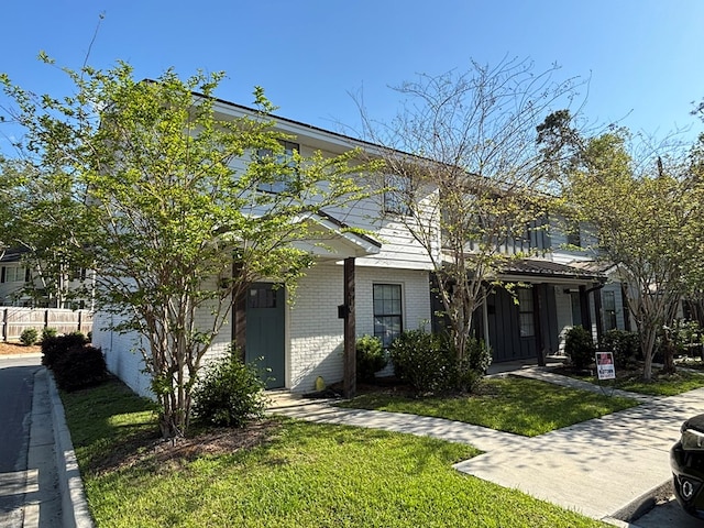 view of front of house featuring brick siding, a front lawn, and fence