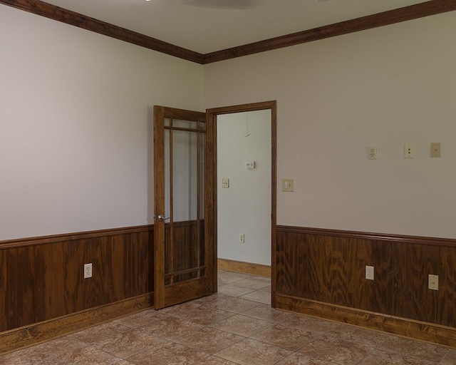 spare room featuring wood walls and crown molding