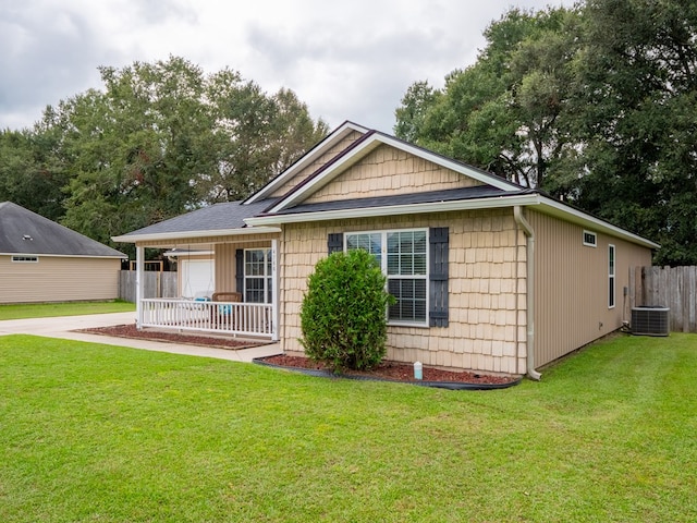 view of front of home with fence, a front lawn, and central AC unit