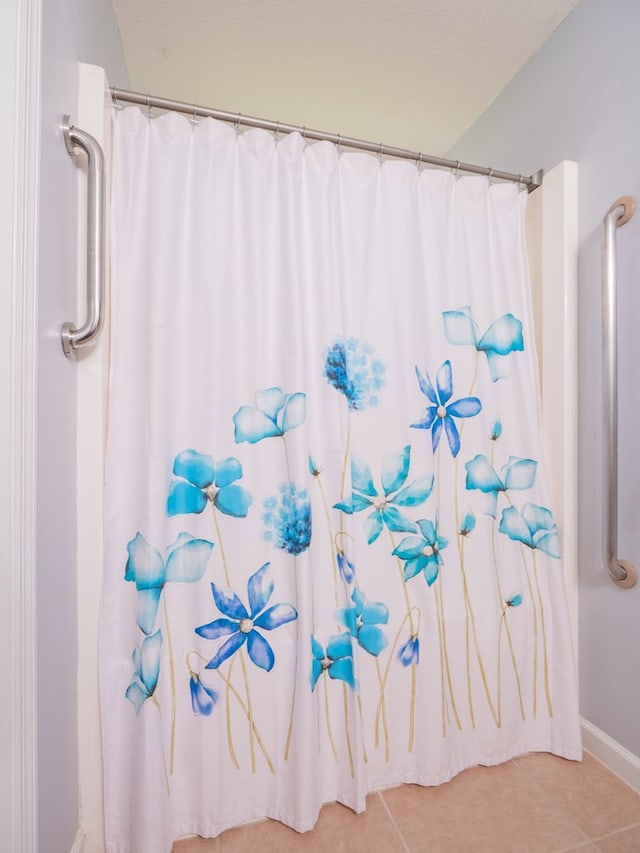 full bathroom with curtained shower, a textured ceiling, and tile patterned floors