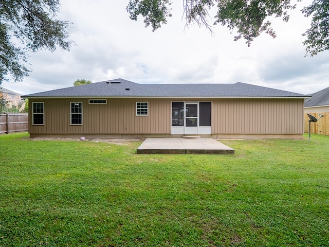 rear view of property featuring a patio, a lawn, and fence