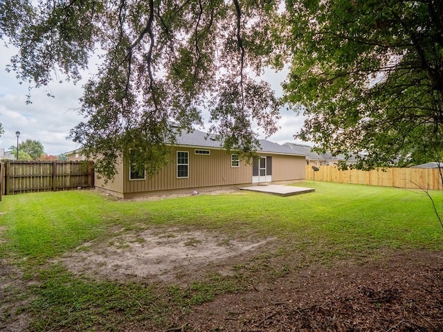 back of property featuring a fenced backyard and a lawn