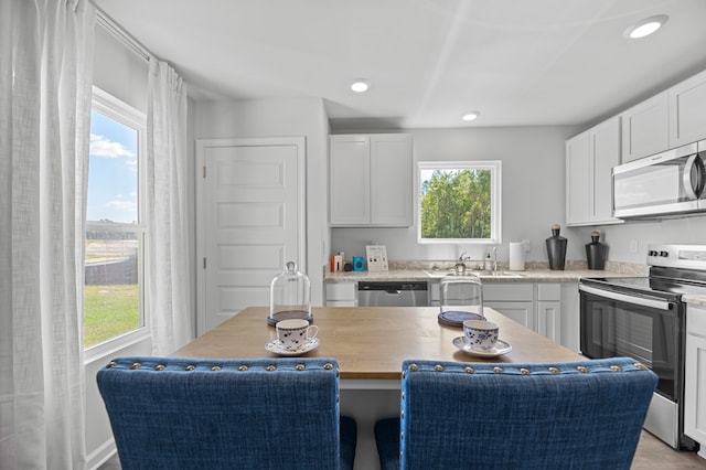 kitchen featuring a kitchen island, appliances with stainless steel finishes, white cabinetry, a sink, and recessed lighting