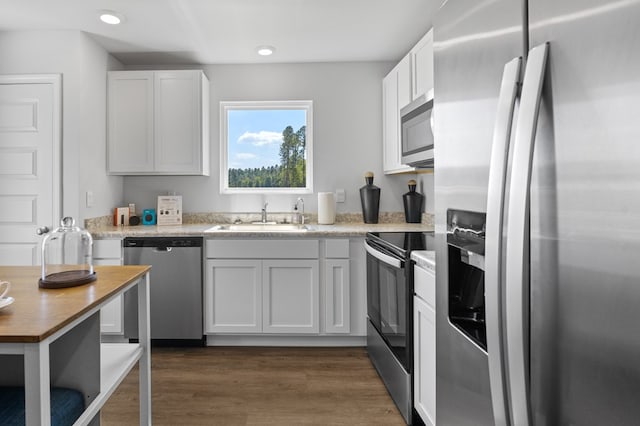 kitchen with dark wood-style floors, stainless steel appliances, light countertops, white cabinetry, and a sink