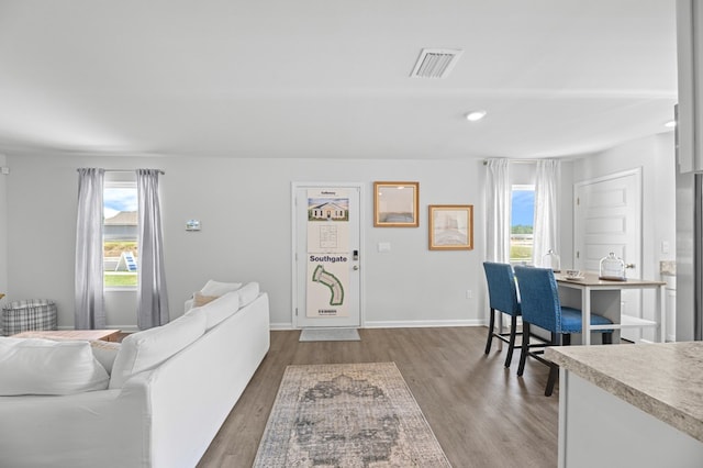 living room with a healthy amount of sunlight, visible vents, baseboards, and wood finished floors