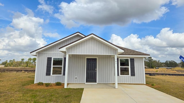 view of front facade with a shingled roof, board and batten siding, and a front yard