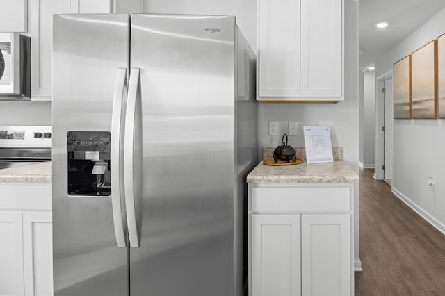 kitchen with light countertops, appliances with stainless steel finishes, white cabinetry, wood finished floors, and baseboards