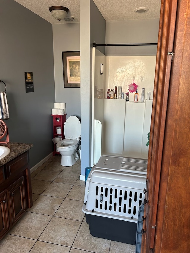 bathroom featuring vanity, tile patterned floors, toilet, and a textured ceiling