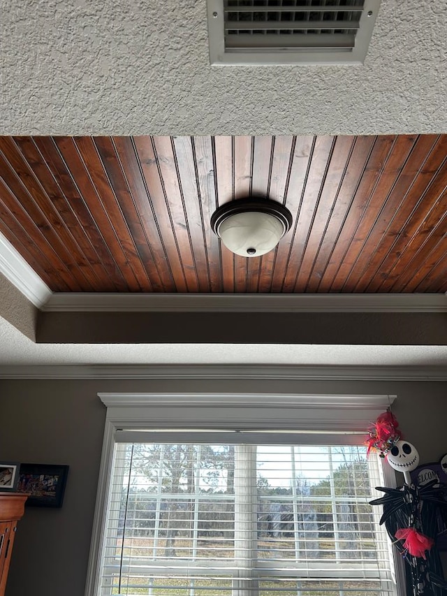 interior details featuring a raised ceiling, ornamental molding, and wood ceiling