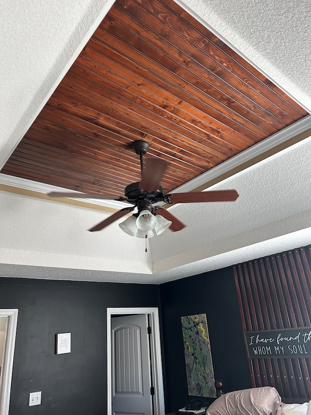 room details featuring ceiling fan, a textured ceiling, and wooden ceiling