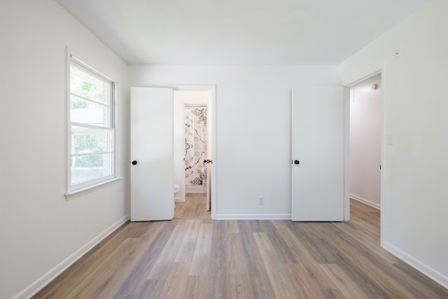 unfurnished bedroom featuring connected bathroom and light hardwood / wood-style floors