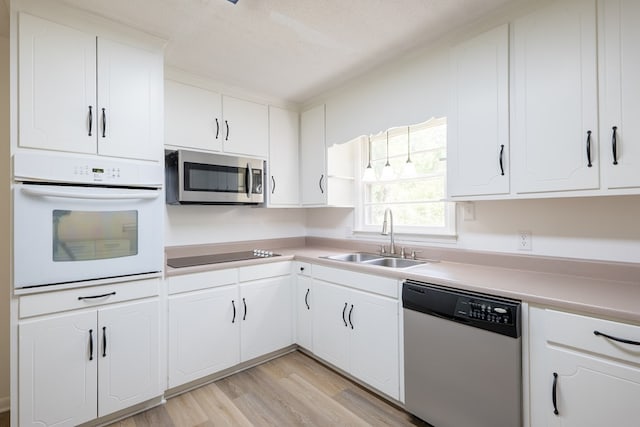 kitchen featuring white cabinets, sink, light wood-type flooring, a textured ceiling, and stainless steel appliances