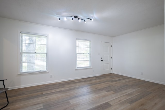 empty room with a wealth of natural light, hardwood / wood-style floors, and a textured ceiling