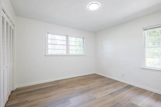 unfurnished bedroom with a closet, light hardwood / wood-style floors, and multiple windows