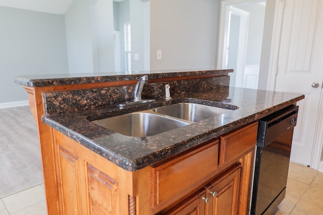 kitchen featuring black dishwasher, light tile patterned floors, a sink, and a kitchen island with sink