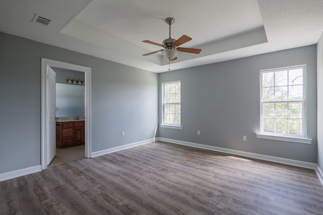 unfurnished bedroom with dark wood-style floors, baseboards, and a raised ceiling