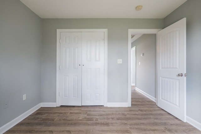 unfurnished bedroom featuring a closet, baseboards, and wood finished floors