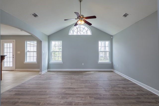 unfurnished room featuring arched walkways, plenty of natural light, and visible vents