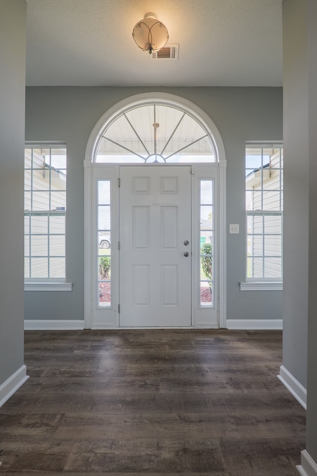 foyer featuring dark wood-style flooring, visible vents, and baseboards